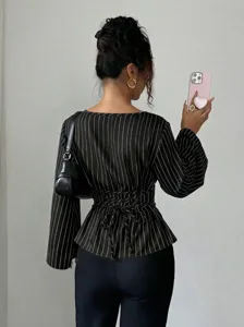 Back view detail of black pinstripe long sleeve blouse with stylish lace up waist design.