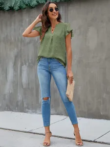 Detail view of summer V-neck ruffle sleeve pom pom chiffon top paired with ripped jeans.
