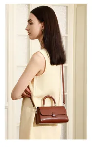 Detailed close-up view of elegant women's brown leather handbag with handle and strap.