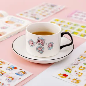 White ceramic coffee cup and saucer set with cute cartoon prints on pink desktop background