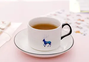 White ceramic coffee cup and saucer set with cute blue elk pattern, elegant desktop tea set.