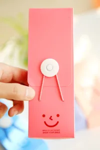 Detailed view of pink candy color plastic pencil case, featuring button closure and smile design.