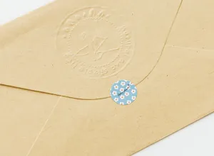Detailed close-up shot of a rustic kraft paper envelope sealed with a cute blue daisy sticker.