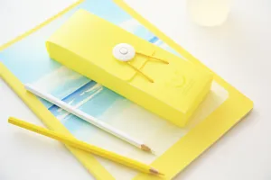 Detail view of yellow candy color pencil box with elastic band button closure and cute smile print.