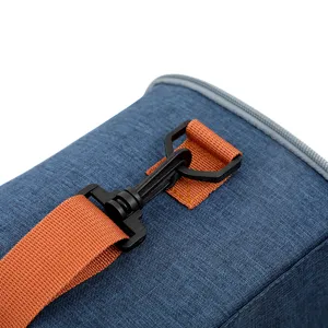 Close up detail of insulated lunch bag, blue fabric texture with orange strap and black buckle.