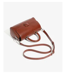 Brown leather top handle bag detail, compact crossbody design with metal hardware and strap.
