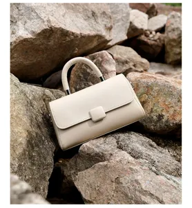 Detail shot of the elegant beige leather handbag displayed outdoors on natural rock surface.