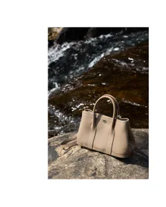 Detail view of the premium leather tote handbag showcased outdoors near a natural rocky stream.