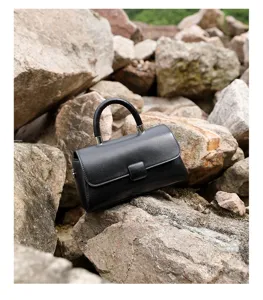 Detail view of a chic black genuine leather handbag, elegant small crossbody bag for use.