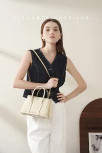 Detail shot of the elegant genuine leather garden handbag in cream white with metal lock.