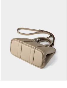Taupe leather handbag bottom detail shot, premium cowhide top handle shoulder bag design.