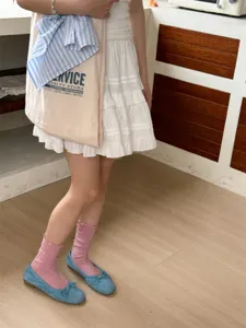 Detailansicht süßer japanischer rosafarbener Rüschen-Mittelsocken mit blauen flachen Schuhen.
