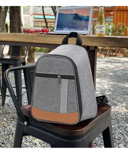 Detailed shot of grey insulated backpack lunch bag placed on outdoor chair with grey fabric.