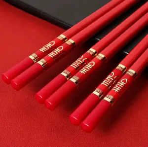 Nahaufnahme roter chinesischer Hochzeitsstaebchen mit goldenen Doppelglueck Motiven und Details.