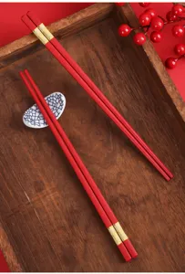 Detailaufnahme von roten Hochzeitsstäbchen mit Goldakzent und Holztablett Dekor.