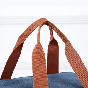 Close-up detail of sturdy brown webbing handles on a blue insulated lunch bag for daily use.
