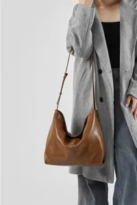 Gedetailleerd shot van een stijlvolle bruine lederen hobo-tas gedragen met een jas.