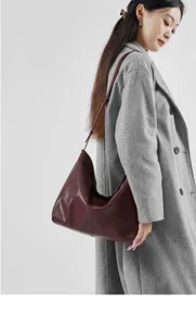 Gedetailleerd overzicht van de elegante bordeauxlederen hobo-schoudertas gedragen door model.