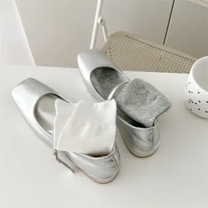 Detailaufnahme einfarbiger Baumwollsocken in metallisch silbernen flachen Schuhen präsentiert.
