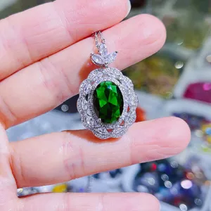 Detailaufnahme eines eleganten ovalen grünen Edelstein-Anhängers mit Zirkonia-Rand.