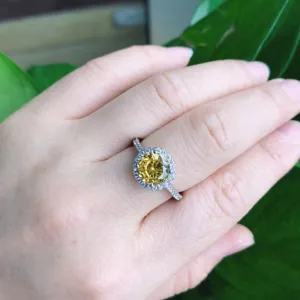 Nahaufnahme eines klassischen 2-Karat gelben synthetischen Edelsteinrings mit funkelndem Halo.