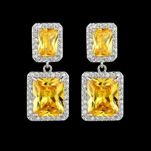 Nahaufnahme eleganter quadratischer Ohrringe mit gelben Zirkonia und weißem funkelnden Rand.