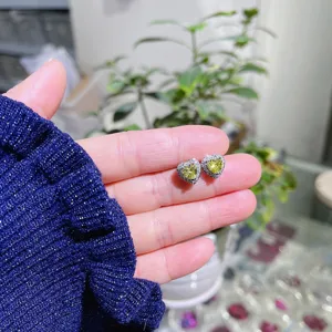 Nahaufnahme von funkelnden gelben Herz Zirkonia Ohrsteckern mit Silberpinnen für Damen.