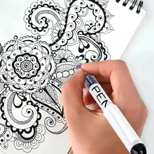 Gedetailleerd aanzicht van een vloeibare gelpen die prachtige bloemmotieven op papier tekent.