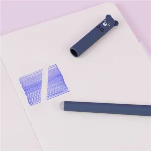 Cute erasable gel pen with bear cap and blue ink writing sample on white notebook detail.