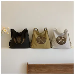 Détail du sac bandoulière en toile, style sac à dos multifonctionnel en trois couleurs classiques.