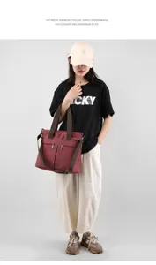 Detailed view of the burgundy canvas shoulder bag, featuring sturdy brown straps and dual zip pockets.