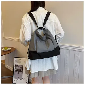 Detailed view of casual canvas backpack featuring grey and black color block design with front pocket.