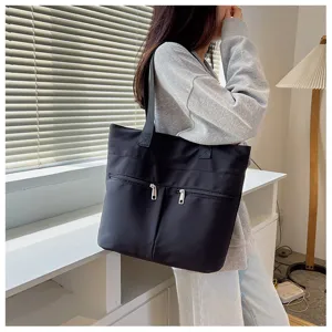 Detail view of black nylon tote bag, featuring double zipper pockets and comfortable shoulder straps.