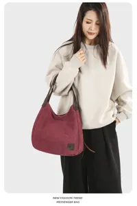 Detailed shot of the burgundy canvas hobo shoulder bag worn by a model, showing style.
