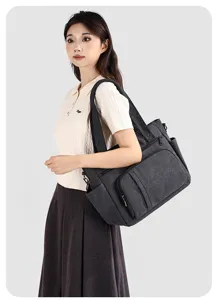 Detail view of dark gray canvas shoulder bag worn by model, showing side utility pockets.