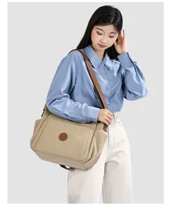 Vue detaillee du sac a bandouliere en toile de grande capacite porte par le mannequin.