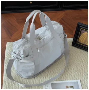 Detailed shot of the light grey travel duffel bag, showing fabric texture and functional straps.