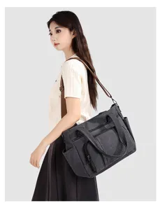 Canvas shoulder bag detail showing model wearing dark grey travel tote bag with cross body strap.