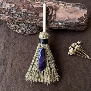 Primo piano dettaglio di un mini ornamento appendiabiti da scopa strega con cristallo viola e paglia.
