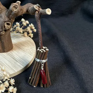 Detail shot of handmade mini twig broom ornament with red crystal and silver wire hanging decor.