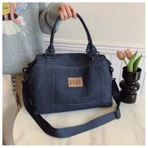 Vista dettagliata della grande borsa a tracolla in denim, tote casual con manici robusti.