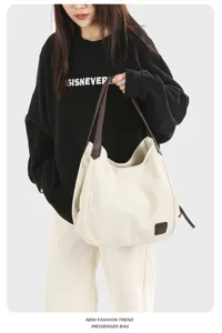 Detail view of casual canvas shoulder bag with brown leather straps worn by model, versatile.