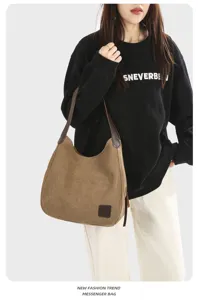 Detailed view of a brown canvas hobo shoulder bag worn on model with leather handles and pockets.