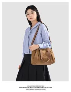 Detailed view of a brown canvas shoulder bag worn by a model, showcasing texture and style.