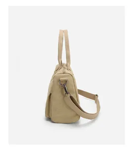 Side view detail of a minimalist beige canvas women handbag with crossbody strap, casual.