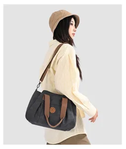 Canvas shoulder bag detail showing the durable fabric, brown strap, and front patch.