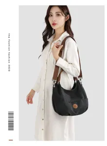 Detailed view of casual black canvas shoulder bag with brown strap and model display.