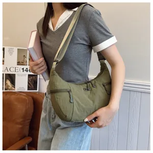 Detail view of casual green nylon crossbody bag with wide strap and multi-pocket design.