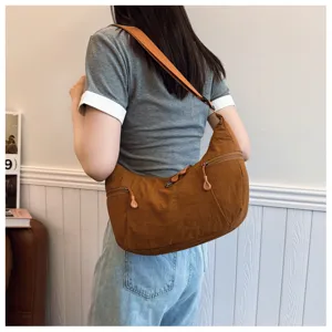 Detail shot of the casual brown nylon shoulder bag showing its curved shape and zipper pockets.