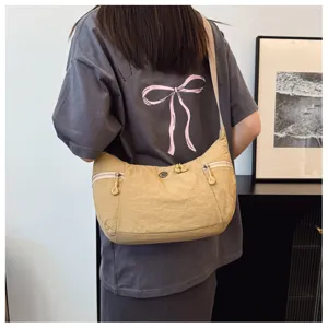 Detail view of lightweight nylon crescent crossbody bag worn casually with dual side zippers.